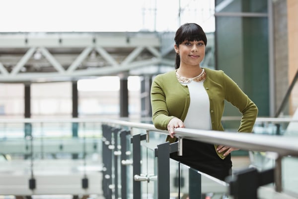 A woman in a green sweater standing in an office building corridor.