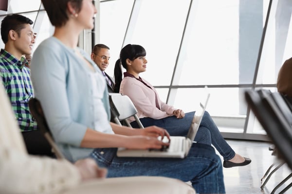 A diverse group of individuals seated in chairs engaged and listening to a discussion.