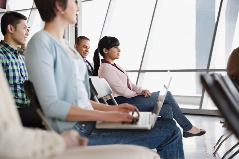 Un groupe diversifié d'individus assis sur des chaises, engagés et écoutant une discussion.