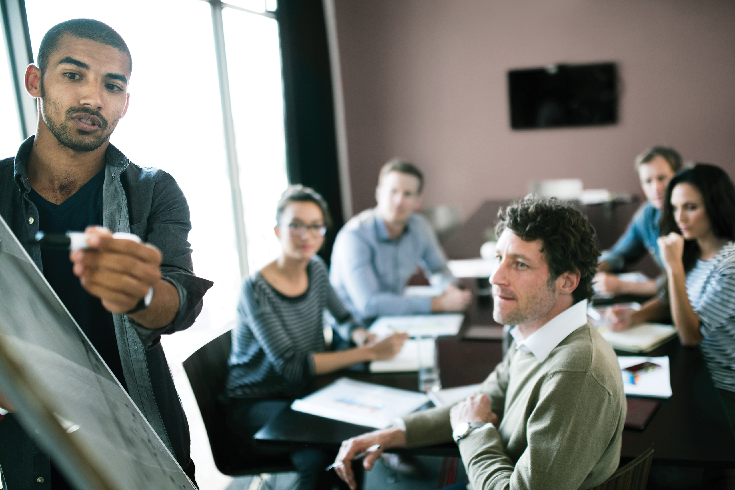 A young professional leading a group brainstorm meeting with coworkers.